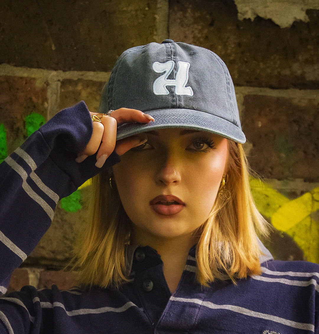 Dziewczyna w czapce z haftowanym H i bluzie rugby – streetwearowy look dla nastolatków i młodych dorosłych