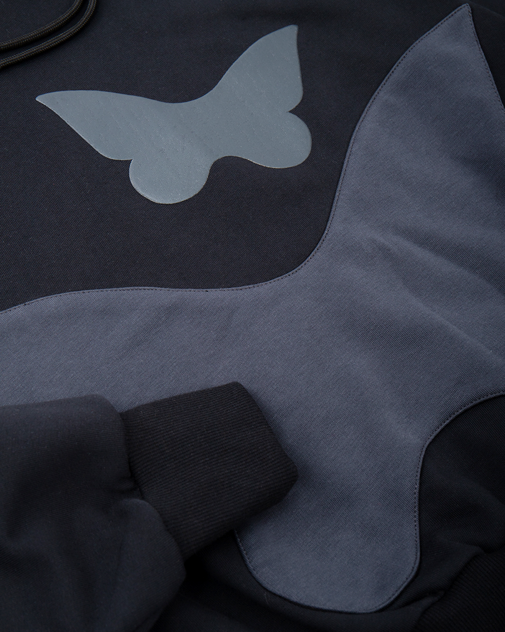 Czarna bluza z motylem na modelu, widoczna duża kieszeń w kształcie motyla oraz mniejsze motylki wykonane puff printem