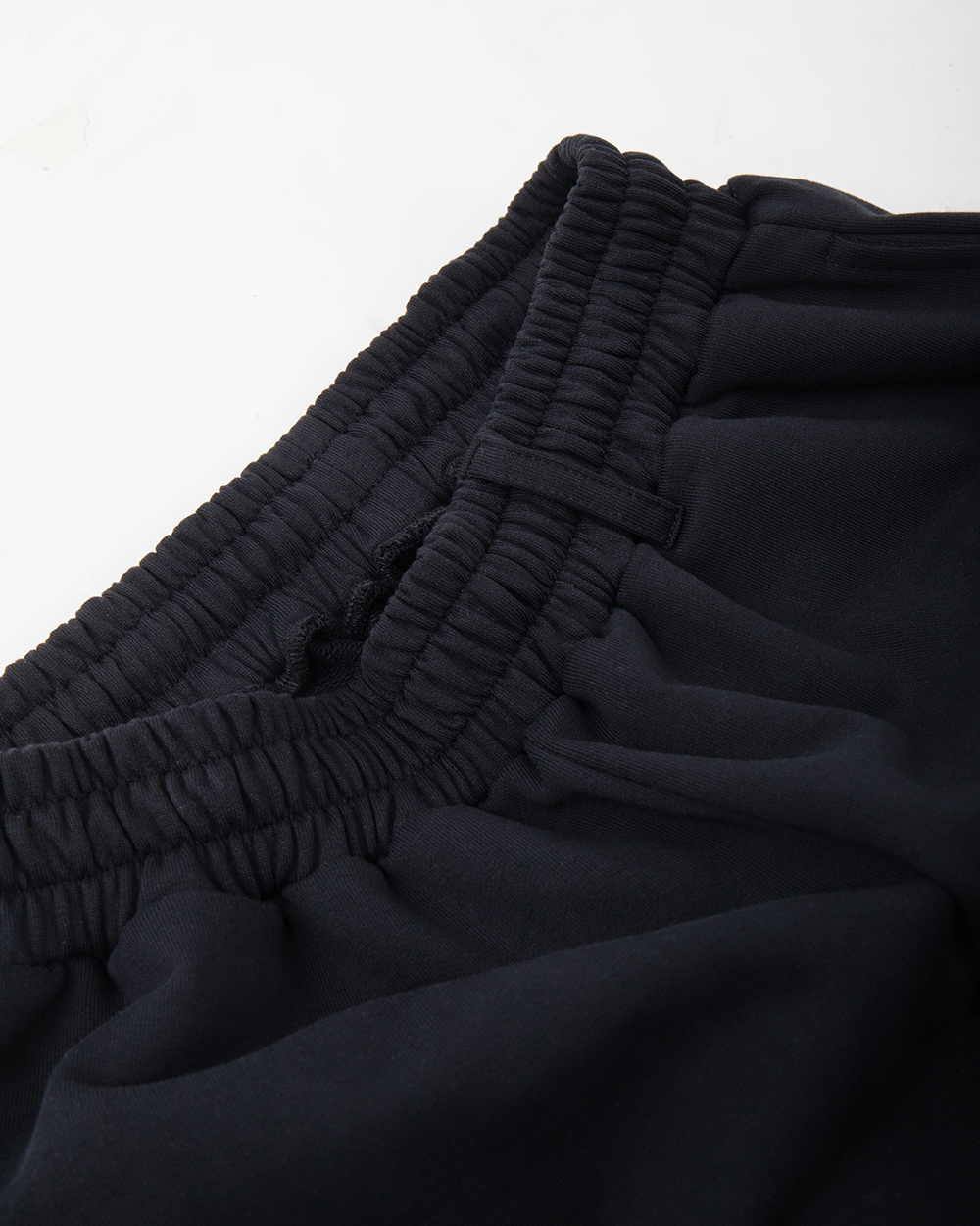 Pojedyncza boczna szlufka w spodniach dresowych baggy, zbliżenie na pas i gęstą dzianinę o wysokiej gramaturze